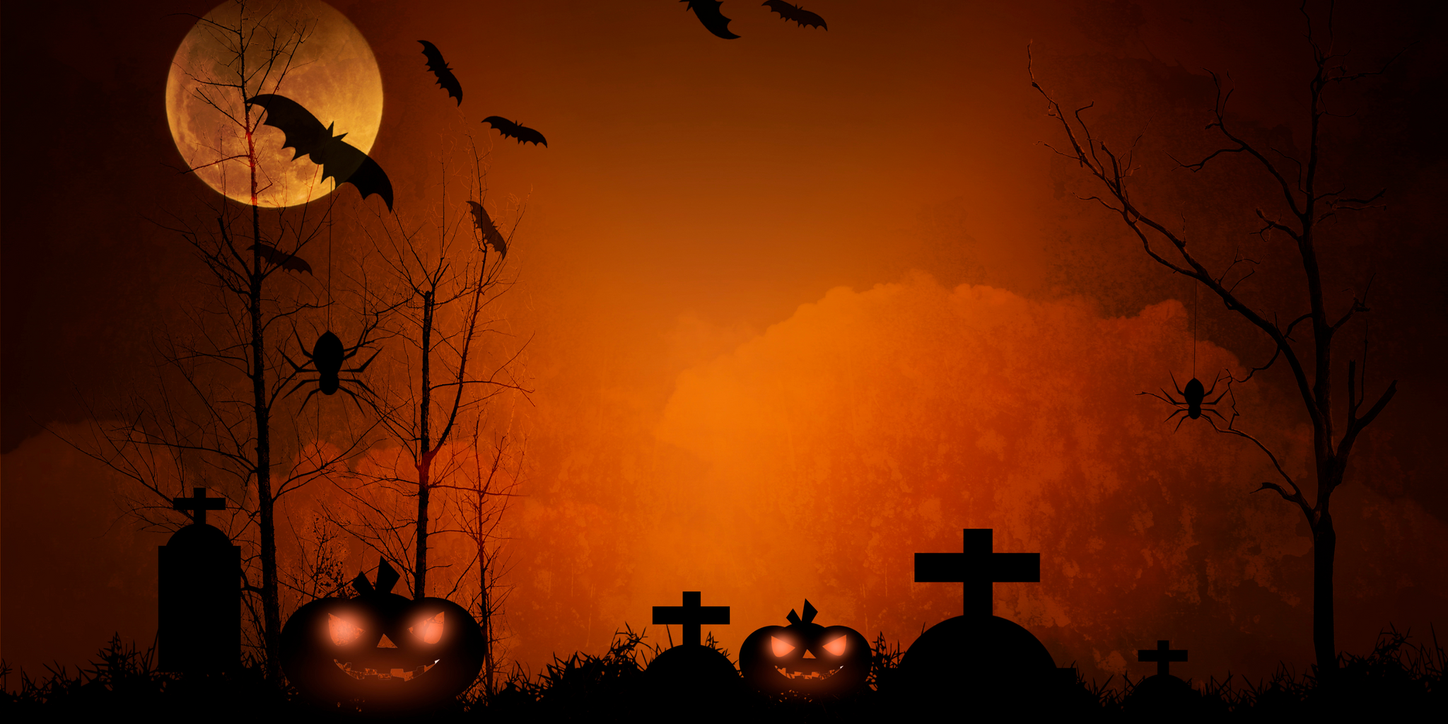Ein Vollmond beleuchtet rot orange einen Friedhof. Kürbisse sind zu sehen. Es ist ein Halloween Bild. 